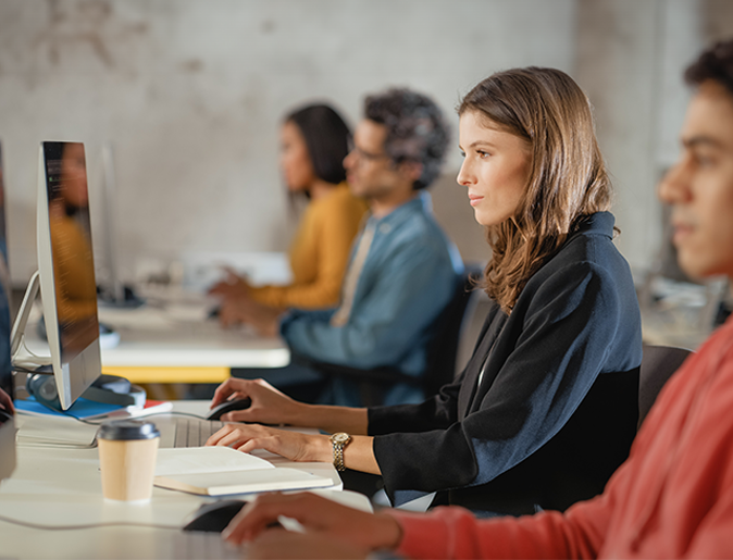 a woman sits at a desk in front of a computer