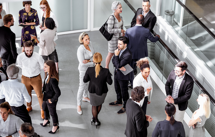 a group of people are standing in a hallway talking to each other