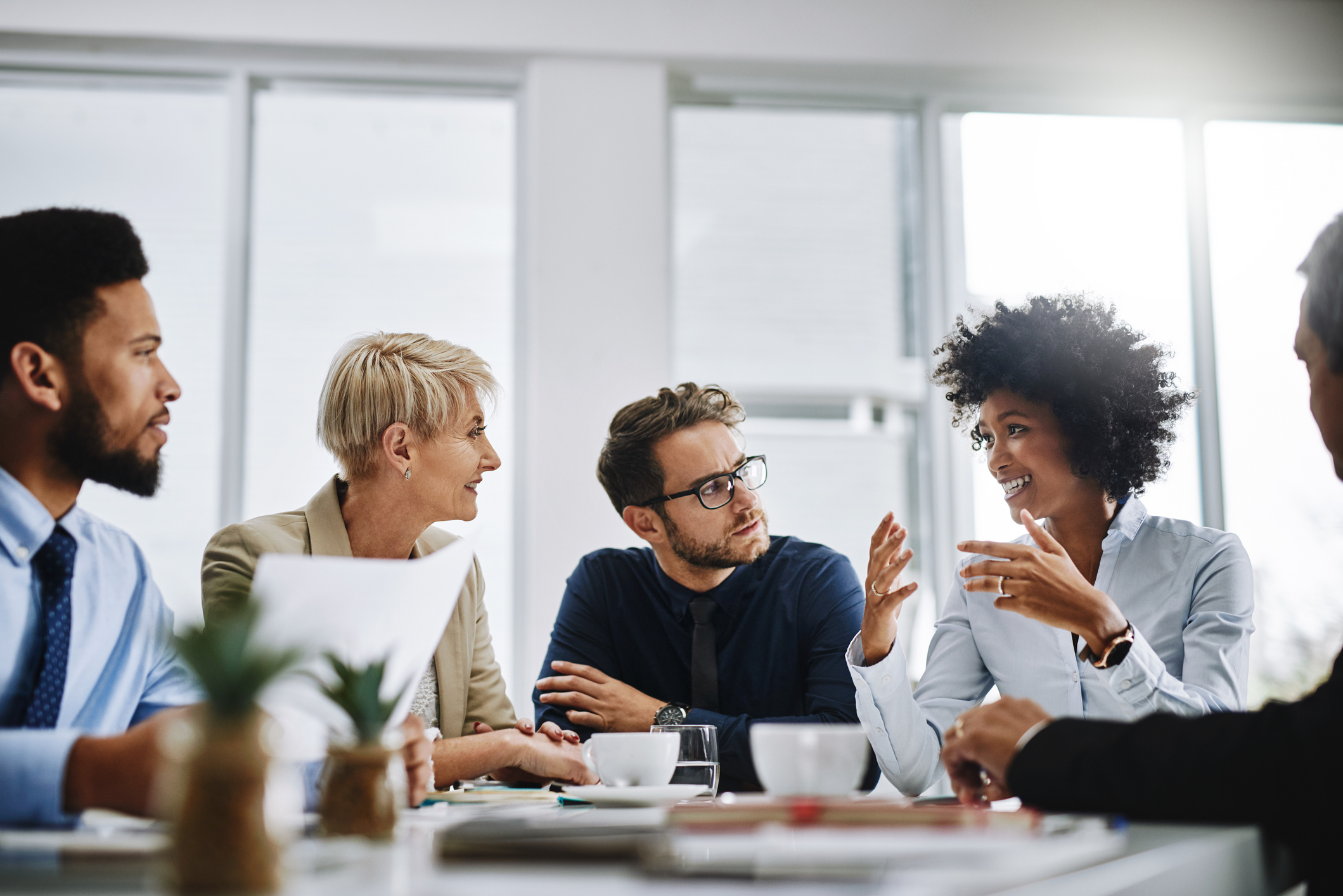 a group of people are sitting around a table having a conversation