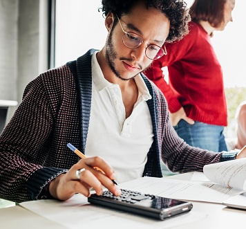 man at his desk using a calculator