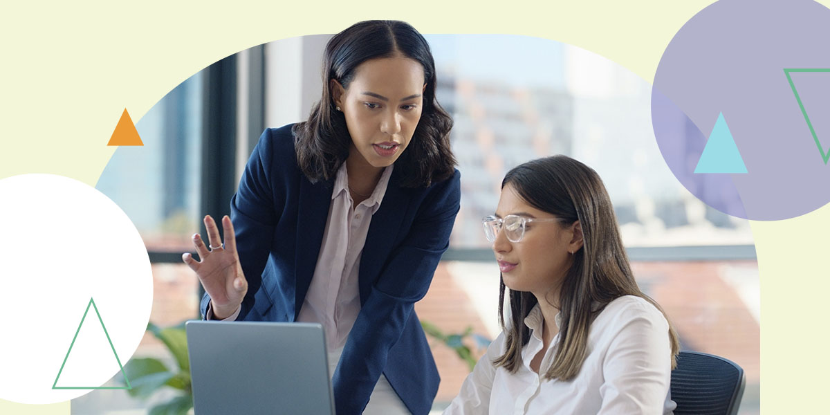 one woman explaining something to another woman looking at her computer
